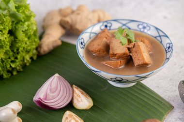 Soya sosu, limonlu ve taze soğanlı seramik bir fincanda kızarır. Muz yapraklarına konur..