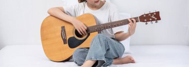 Kız oturdu ve yatakta gitar çaldı..