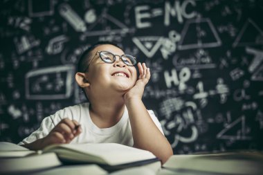 Gözlüklü bir çocuk sınıfta yazıyor.