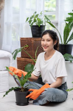 Kadın turuncu eldiven takmış ve eve ağaç dikmiş..