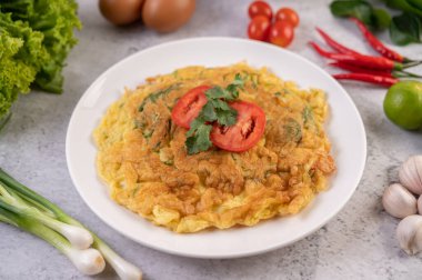 Beyaz bir tabakta domates ve kişniş ile süslenmiş omlet..
