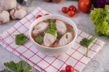 Domuz etiyle doldurulmuş kalamar çorbası, kişniş serpiştirilmiş yeşil soğan ve beyaz bardaklarda doğranmış soğan..