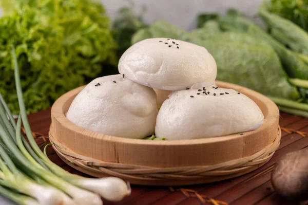 Steamed buns in a wooden dish on a wooden grill. Selective focus.