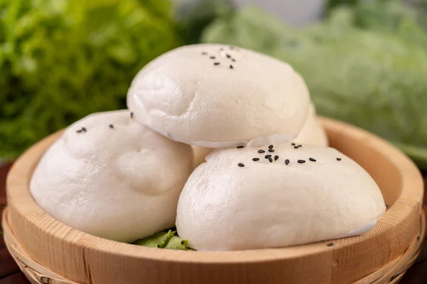 Steamed buns in a wooden dish on a wooden grill. Selective focus.