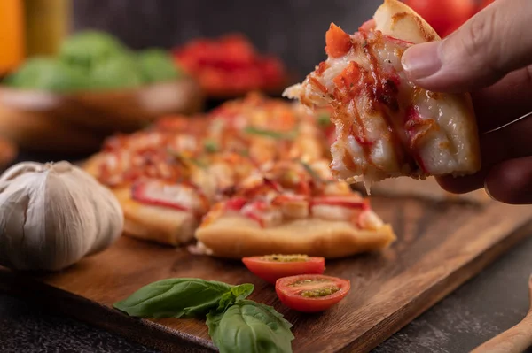 Biber tohumlarıyla dolu tahta bir tabağa yerleştirilmiş pizza. Domates ve sarımsak..