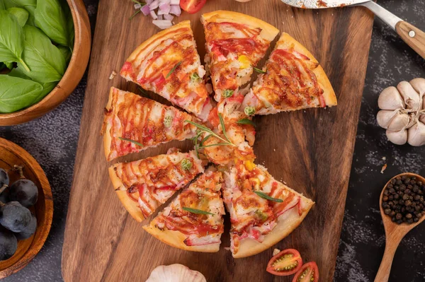 Biber tohumlarıyla dolu tahta bir tabağa yerleştirilmiş pizza. Domates ve sarımsak. Üst görünüm.
