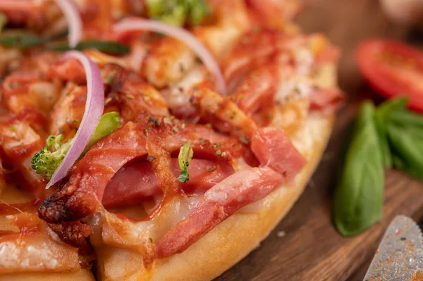 Biber tohumlarıyla dolu tahta bir tabağa yerleştirilmiş pizza. Domates ve sarımsak. Seçici odak.