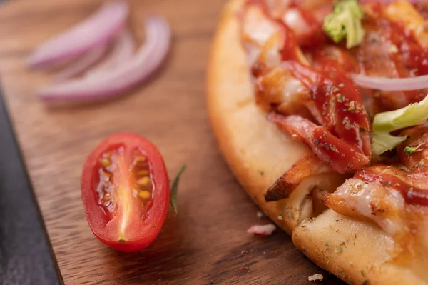 Biber tohumlarıyla dolu tahta bir tabağa yerleştirilmiş pizza. Domates ve sarımsak. Seçici odak.