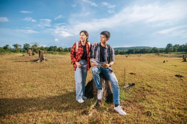 Hem erkek hem de kadın turistler çimlerin üzerinde duran bir sırt çantası taşıyorlar. Ve yana bak..