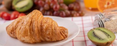 Turuncu ve kivili beyaz tabakta kruvasan..