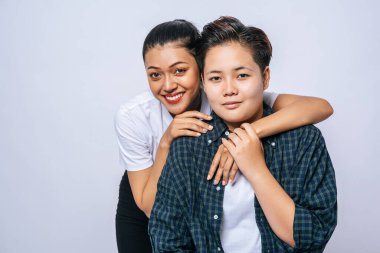 Ayakta duran ve arkadan sarılan iki kadın aşık.