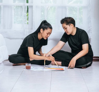 Dişi çiftler kağıda çizer ve boyarlar..