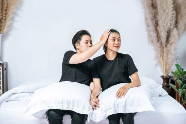 Birkaç kadın bacaklarını desteklemek için yastıklarla yatağa oturdu..