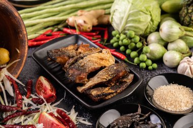 Kızarmış balık siyah bir tabakta dilimler. Seçici odak.