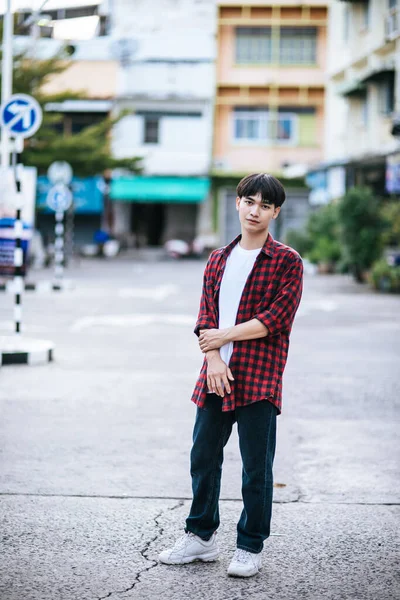 一个穿着条纹衬衫的年轻人站在街上 — 图库照片