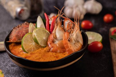 Tom karides, yengeç, limon, kırmızı biber, domates, sarımsak, limon otu ve kaffir limon yapraklı..