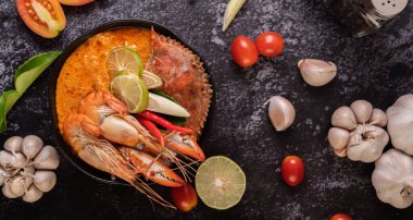 Tom karides, yengeç, limon, kırmızı biber, domates, sarımsak, limon otu ve kaffir limon yapraklı..