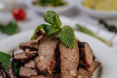 Dilimlenmiş limon, havuç, biber, taze soğan ve naneli ızgara ciğer dilimleri..