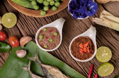 Karides ezmesi, uskumru, muz yaprakları, acı biber, domates, ahşap zeminde sarımsak ve limon..