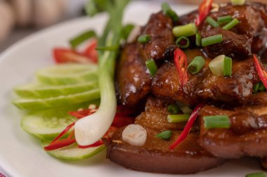 Pirzola, biber, limon, salatalık, domates ve sarımsaklı beyaz bir tabakta tatlı domuz eti..