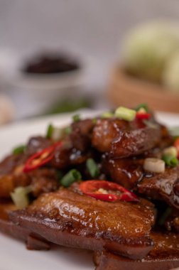 Kırmızı biber ve doğranmış soğan serpilmiş beyaz tabakta tatlı domuz eti..