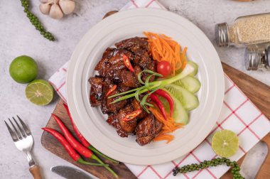 Pirzola, biber, limon, salatalık, domates ve sarımsaklı beyaz bir tabakta tatlı domuz eti..