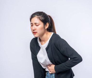 Karın ağrısı olan ve elini karnına bastıran bir kadın..