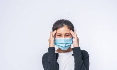 Baş ağrısı olan hasta bir kadın maske taktı ve elini başına koydu..