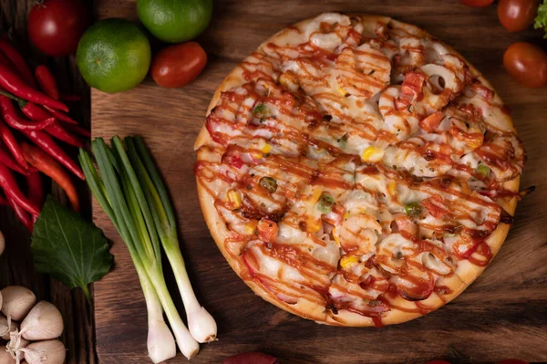 Pizza with sausage, corn, beans, shrimp and bacon on a wooden plate