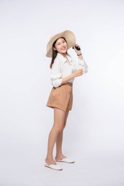 Beyaz gömlek ve şort giyen, şapka takan ve şapka takan genç bir kadın..