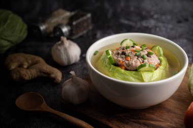 Havuçlu lahana çorbası, doğranmış yeşil soğan, ahşap tabakta salatalık..