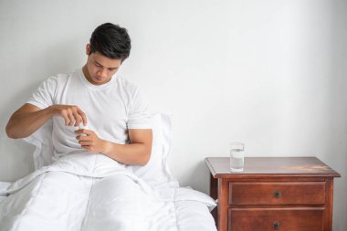 Kanepede hasta ve antibiyotik almak üzere olan bir adam..