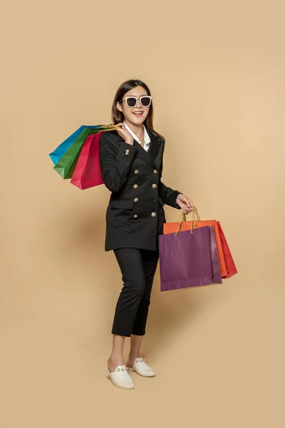 这个女人穿着黑色的衣服 戴着黑色的眼镜 还带着许多袋子去购物 — 图库照片