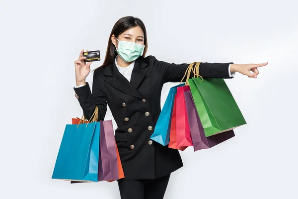 一个戴着面具的黑衣女人走在街上购物 带着信用卡和很多包 — 图库照片