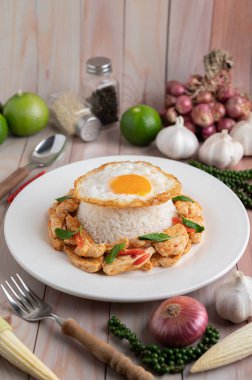 Kızarmış acı biberli tavuk ve pilavlı yumurta ahşap masada beyaz tabakta..