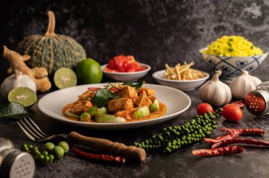 Siyah çimentoda beyaz tabakta tavuklu kuru yeşil köri.