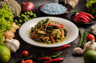 Kızarmış Baharatlı Tavuk 'u beyaz tabakta, siyah çimentoda baharatlarla karıştır.