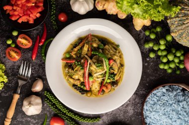 Kızarmış Baharatlı Tavuk 'u beyaz tabakta, siyah çimentoda baharatlarla karıştır.