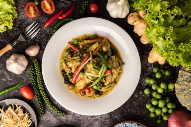 Kızarmış Baharatlı Tavuk 'u beyaz tabakta, siyah çimentoda baharatlarla karıştır.