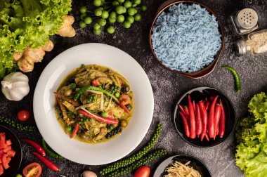 Kızarmış Baharatlı Tavuk 'u beyaz tabakta, siyah çimentoda baharatlarla karıştır.