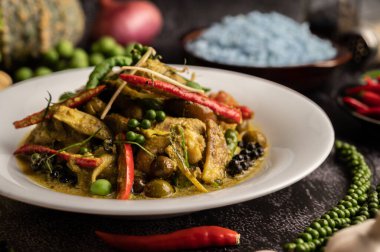 Kızarmış Baharatlı Tavuk 'u beyaz tabakta, siyah çimentoda baharatlarla karıştır.