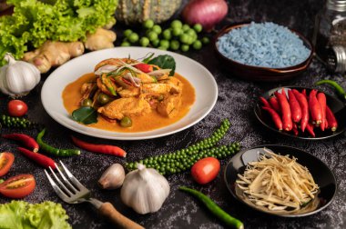 Siyah çimentoda beyaz tabakta tavuklu kuru yeşil köri.