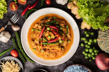 Beyaz tabakta kırmızı köri ve siyah çimentoda baharatlar..