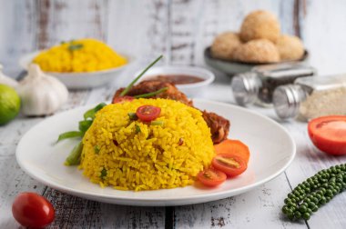 Beyaz ahşap zeminde baharatlı bir tabakta tavuk biryani.