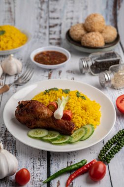 Beyaz ahşap zeminde baharatlı bir tabakta tavuk biryani.