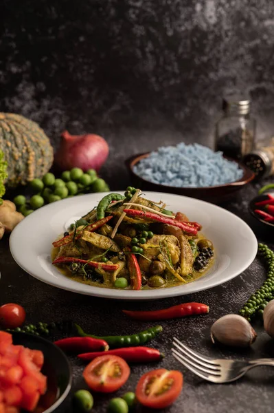 Kızarmış Baharatlı Tavuk 'u beyaz tabakta, siyah çimentoda baharatlarla karıştır.