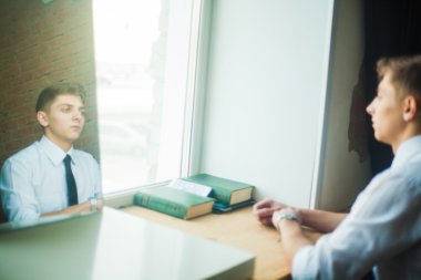 Pencere ve bir tuğla duvara yakın duran genç çekici adam