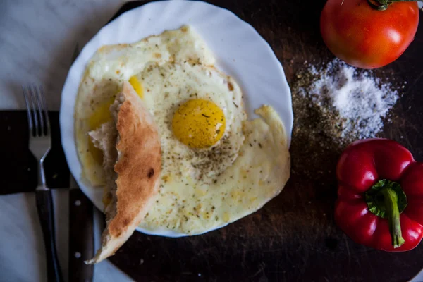 Closeup of plate with fried eggs and tomatoes near fork and knife — Stock Photo, Image
