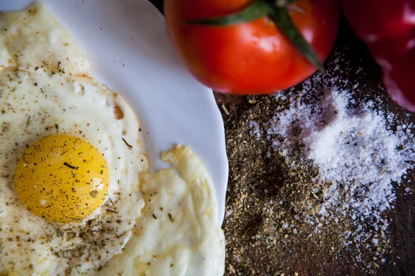 Крупним планом тарілку зі смаженими яйцями та помідорами біля виделки та ножа — стокове фото