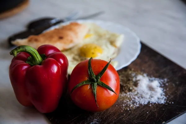 Closeup of plate with fried eggs and tomatoes near fork and knife — Stock Photo, Image